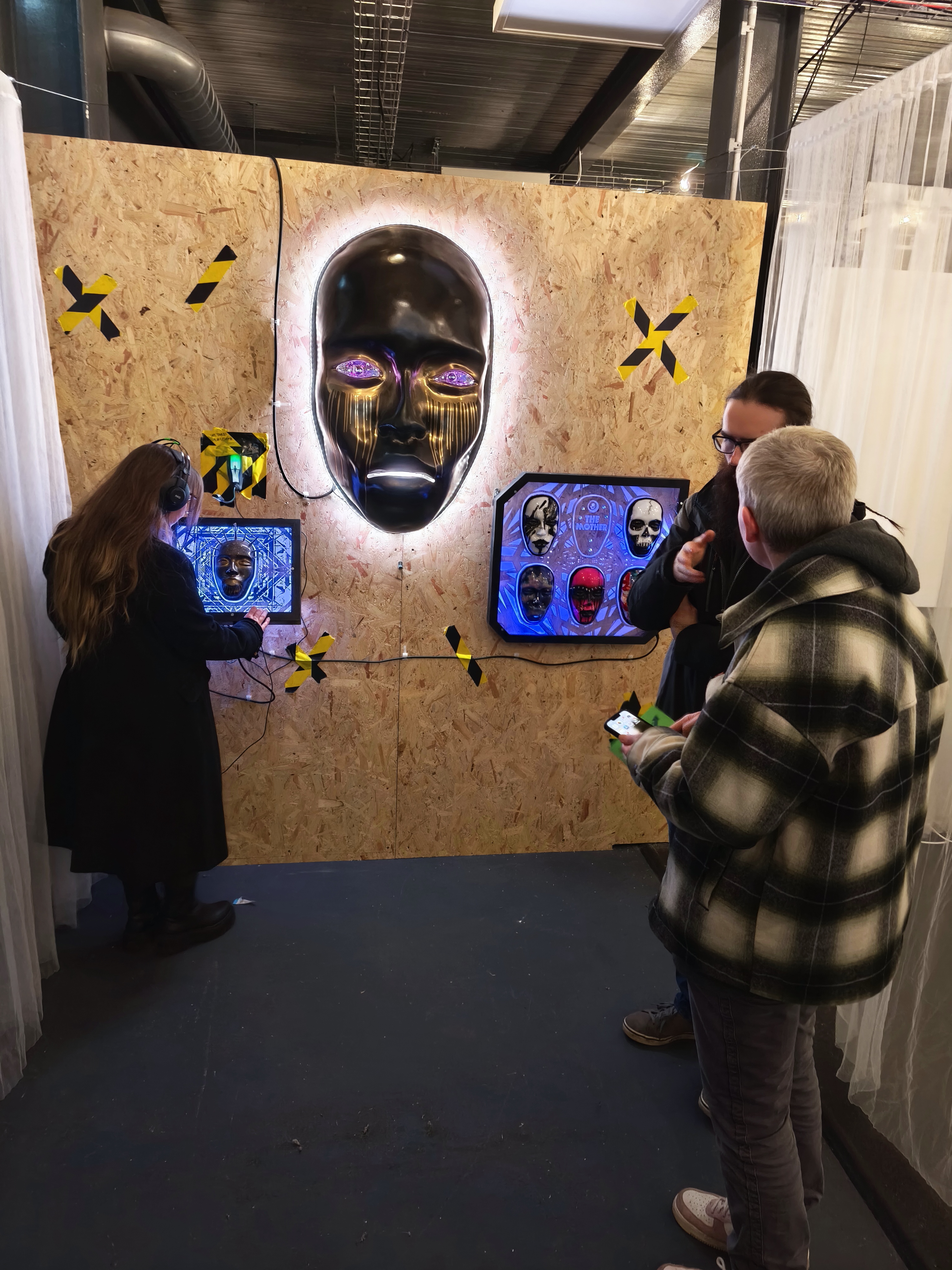 Visitors engaging with the AILA installation at exhibition — one with headphones interacting with the plinth