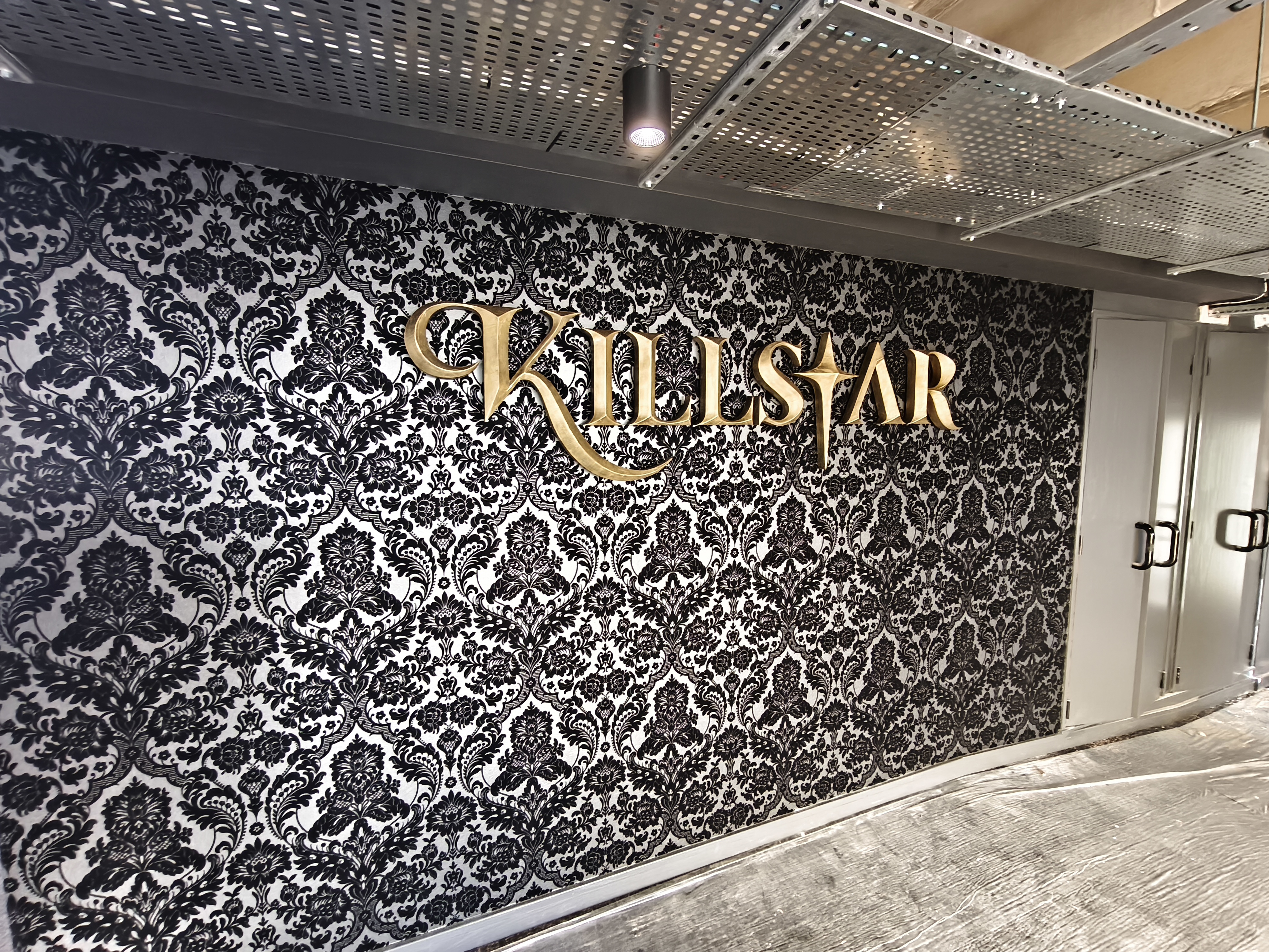 Killstar sign installed on damask wall, full sign visible, room still being fitted