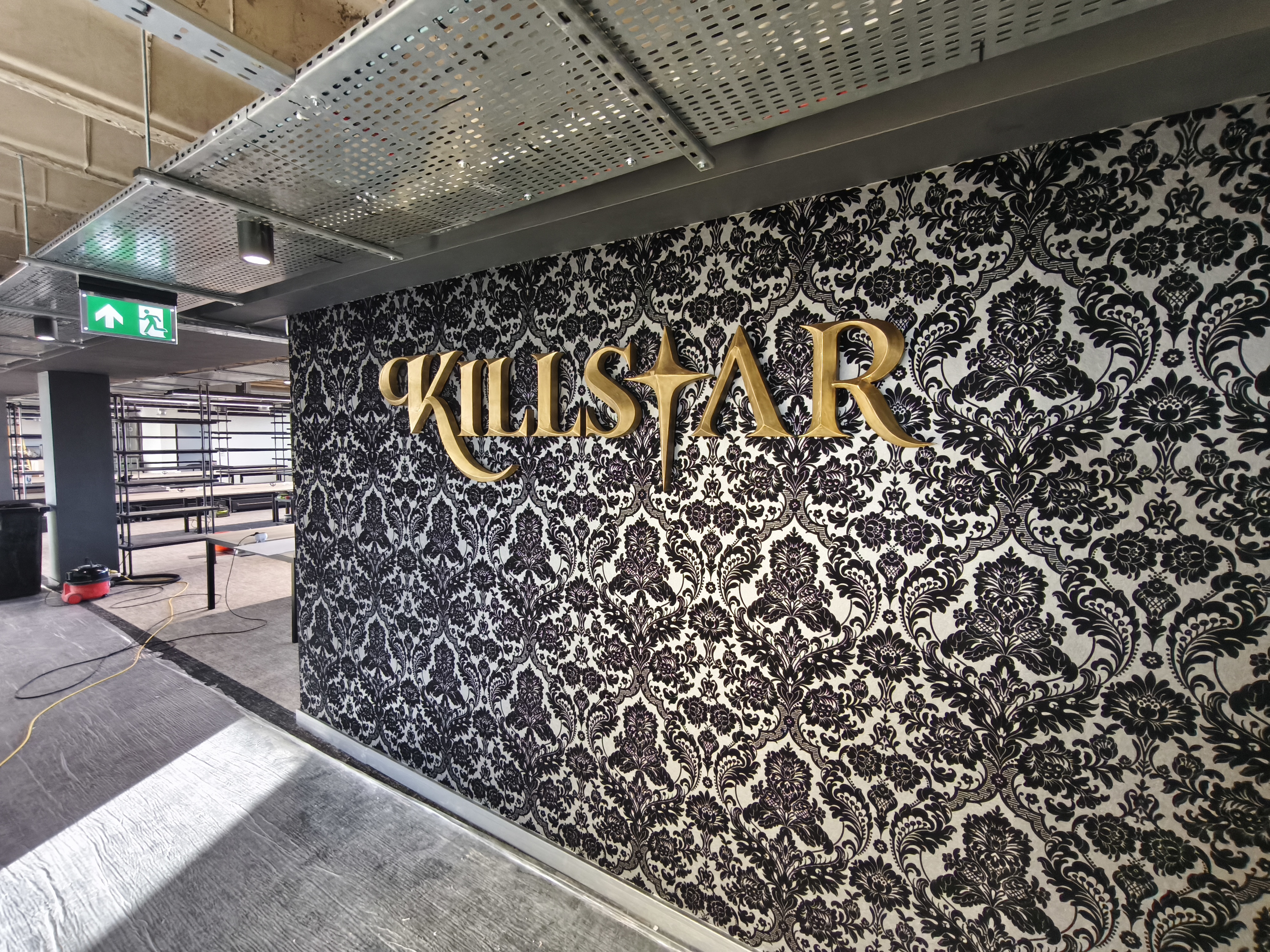 Killstar signage installed, closer view showing lettering against damask wallpaper